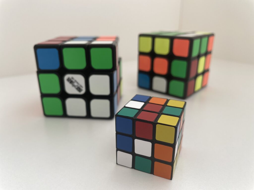 Tre Rubiks kuber på et bord, symboliserer mystik og underholdning til fester.